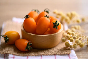 Orange cherry tomatoes in wooden bowl, fresh organic vegetable