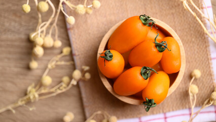Obraz na płótnie Canvas Orange cherry tomatoes in wooden bowl, fresh organic vegetable