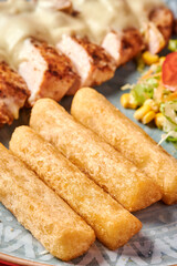 primer plano de yuca frita con pollo asado de fondo