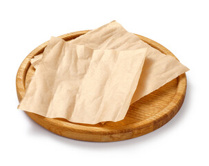 Baking paper on wooden board isolated. Round board with crumpled pieces of brown parchment or...