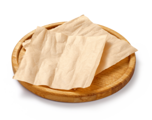 Baking paper on wooden board isolated. Round board with crumpled pieces of brown parchment or baking paper on white background. Design element.