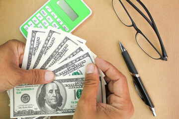 hand counting dollar bills with calculator, glasses and pen background. business man working financial adviser and counting money banknotes
