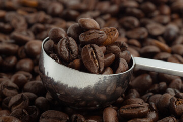 coffee beans in a stainless spoon on coffee bean background.