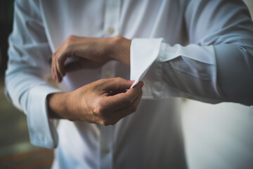 Man tying cufflinks in white shirt