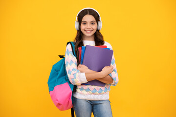 Schoolgirl, teenage student lifestyle girl in headphones hold books on yellow isolated studio...