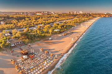 Naklejka premium Aerial view of scenic and popular Konyaalti beach in Antalya resort town. Majestic mountains with haze in the background. Vacation and holiday in Turkiye