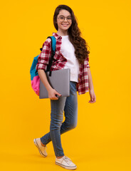 Schoolchild, teenage student girl with laptop on yellow isolated studio background. Children school...