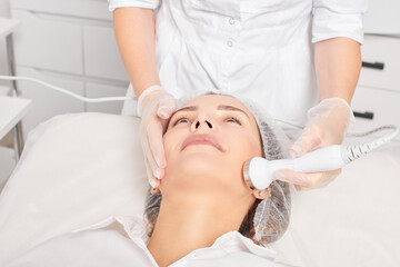 Beautician makes ultrasound skin tightening for rejuvenation woman face using phonophoresis, anti...