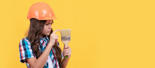 improvement. making surface repair. serious teen girl hold painting brush. child painter. Child builder in helmet horizontal poster design. Banner header, copy space.