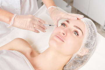 Cosmetologist makes rejuvenation injection in woman face, anti aging non surgical cosmetic...