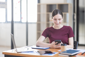 Portrait of Young canada american business woman using a mobile phone and works on a laptop computer in the modern home workplace office