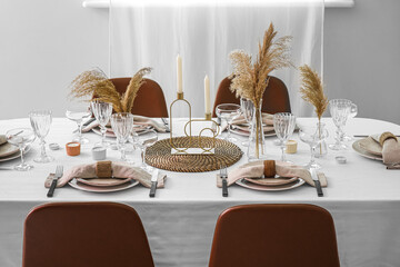 Beautiful table setting with vases, pampas grass and candles in room