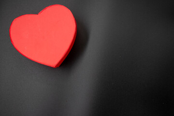 Red heart shaped gift box and dried red rose leafs on black background,Valentine's Day or birthday concept, copy space area 