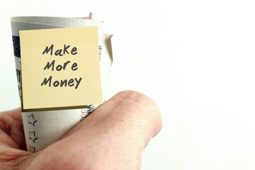 Hand holding cash dollars money with sticky note MAKE MORE MONEY, refers to financial goal to make...