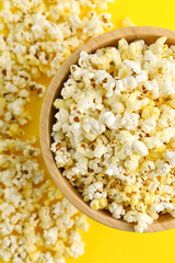 Bowl of tasty popcorn on yellow background, closeup