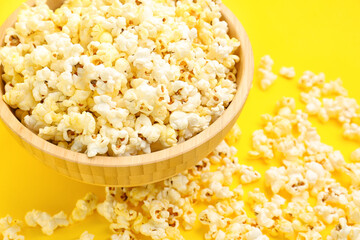Bowl of tasty popcorn on yellow background, closeup