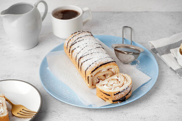 Blue plate with delicious sponge cake roll and cup of coffee on white table