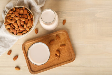 Board with glass, bottle of almond milk and nuts on wooden background