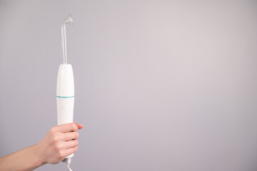 Woman holding darsonval apparatus on white background. 