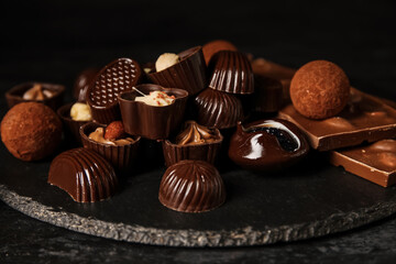 Board with chocolate candies on dark table