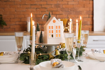 Christmas table setting with candle holders and fir trees in kitchen, closeup