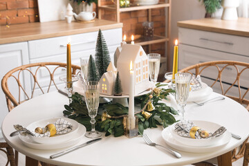Christmas table setting with candle holders and fir trees in kitchen
