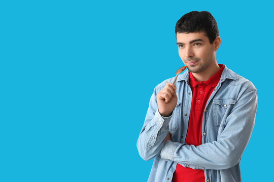 Young man with tablespoon on blue background