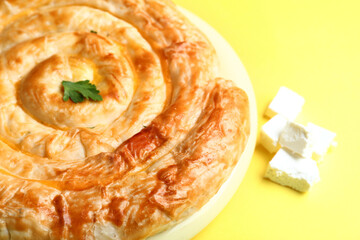 Plate with delicious cheese pie on yellow background