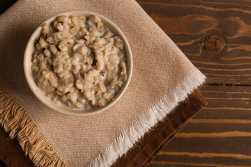 Bowl with tasty oatmeal and napkins on wooden background