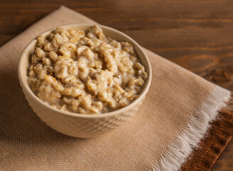 Bowl with tasty oatmeal and napkins on wooden background