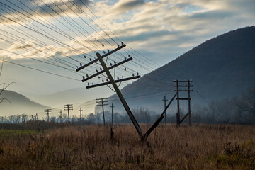 Autumn field with fallen electric poles at dawn. The wires were stretched dangerously under the...