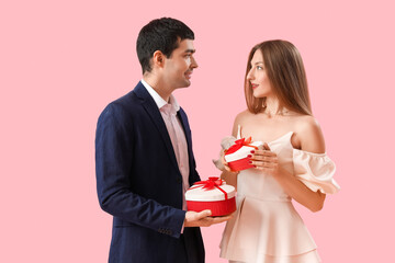 Young couple in love with gifts on pink background. Valentine's Day celebration