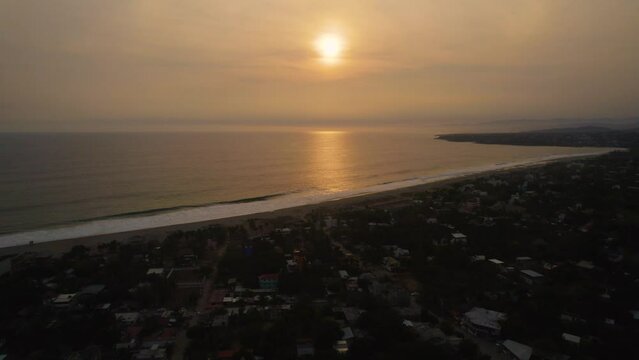 Backward aerial dolly shot with the sun setting over the ocean at Puerto Escondido