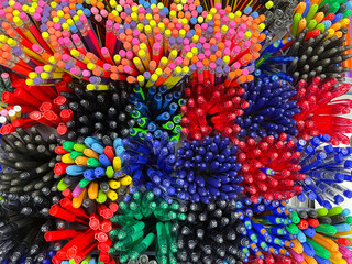 Pile of pens and pencils of different colours. Background texture. Selective focus