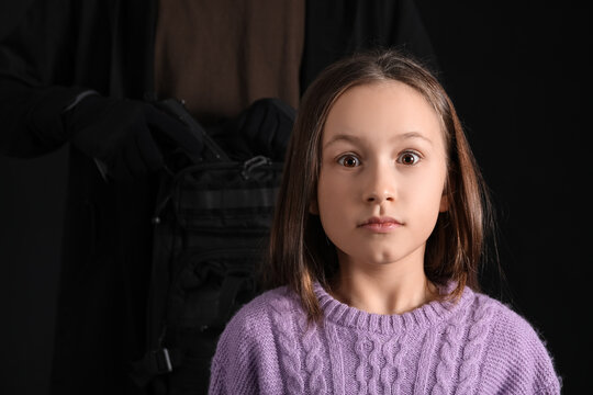 Terrorist and scared little hostage on black background