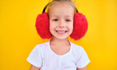 happy Cute smiling little girl stylish winter earmuffs light yellow background