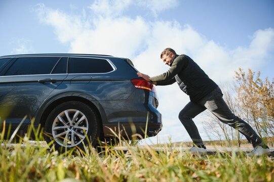 Man Pushing A Broken Car Down The Rock Road