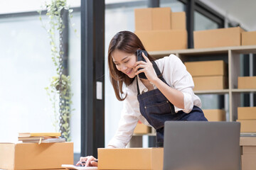 Young Asian Woman Working at home, Young Owner Woman talking to customer and working with happy emotion. People with online shopping SME entrepreneur or freelance working concept.