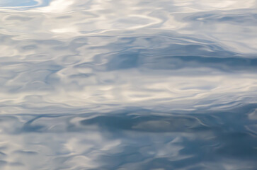Beautiful abstract watercolor natural background of rippled water surface with distorted shapes, fluffy clouds and blue sky reflections. Copy space for​ graphic​ design of posters or banners