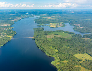 View of airplane wing, blue skies and green land and river during landing. Airplane window view.