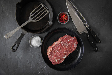 Entrecote Steak roh vom Rind mit Meersalz und roter Pfeffer auf Teller bei Vorbereitung in Küche...