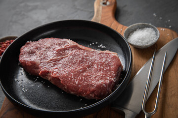 Entrecote Steak roh vom Rind mit Meersalz und roter Pfeffer auf Teller bei Vorbereitung in Küche...