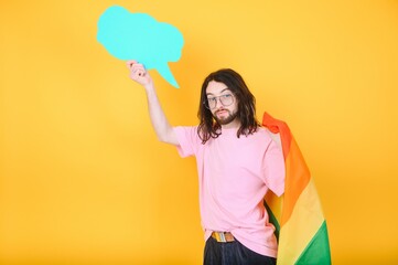 Gay man wearing bright pink top hold rainbow striped flag isolated on colored background studio portrait. People lifestyle fashion lgbtq concept
