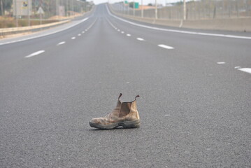 Old boot, useless item, on empty highway. Solitude concept