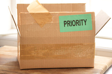 Shipping concept. Online purchase delivery cardboard box with word priority sticker. Important purchase. Expedited parcel