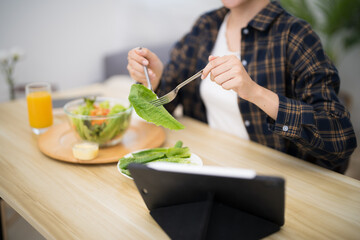 Happy beautiful Asian woman eating healthy food with vegan.salad in the kitchen at home.