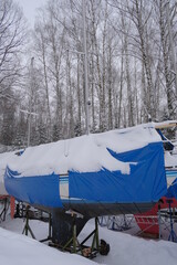 Yacht, boat, ship on the shore under a canopy awning in the snow