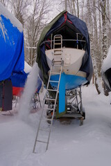 A yacht covered with an awning for the winter, from which snow is removed