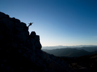 silhouette of mountaineer descending from cliff on cliff