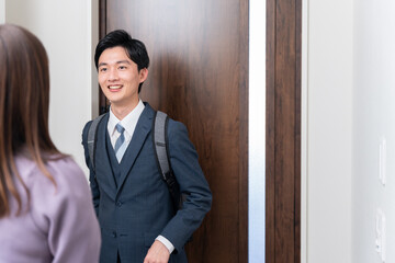 出勤する夫と玄関で見送る妻（夫婦・カップル）